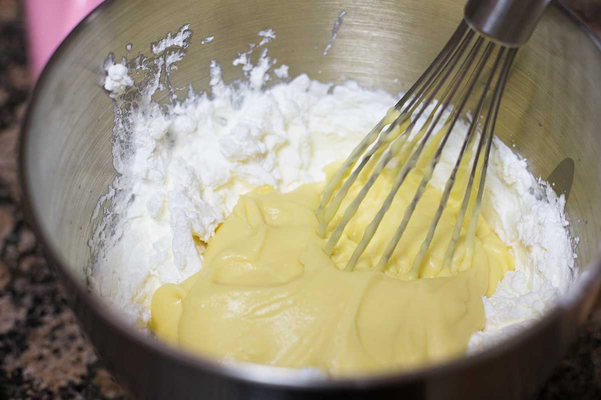 Whisking zabaglione into whipped cream and mascarpone in a bowl 