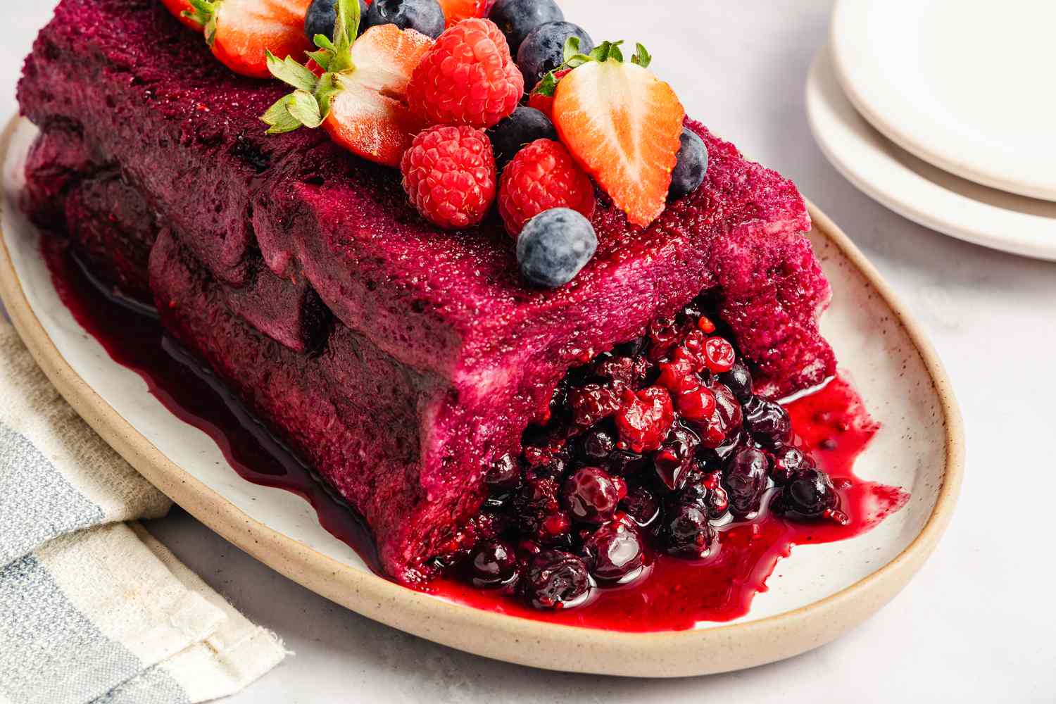 A summer pudding topped with various berries served on a platter