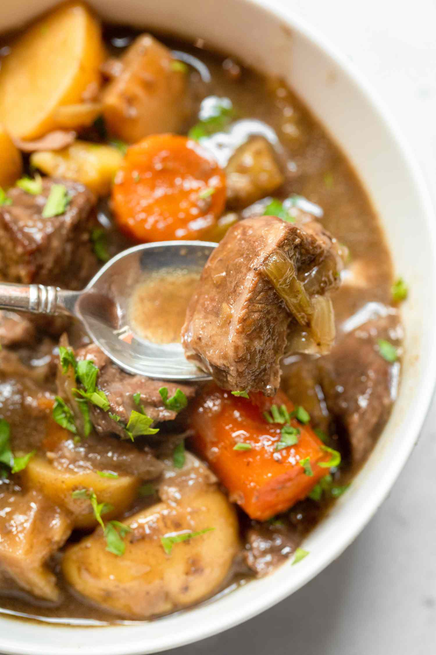 Slow Cooker Beef Stew in a Bowl with a Piece on a Spoon