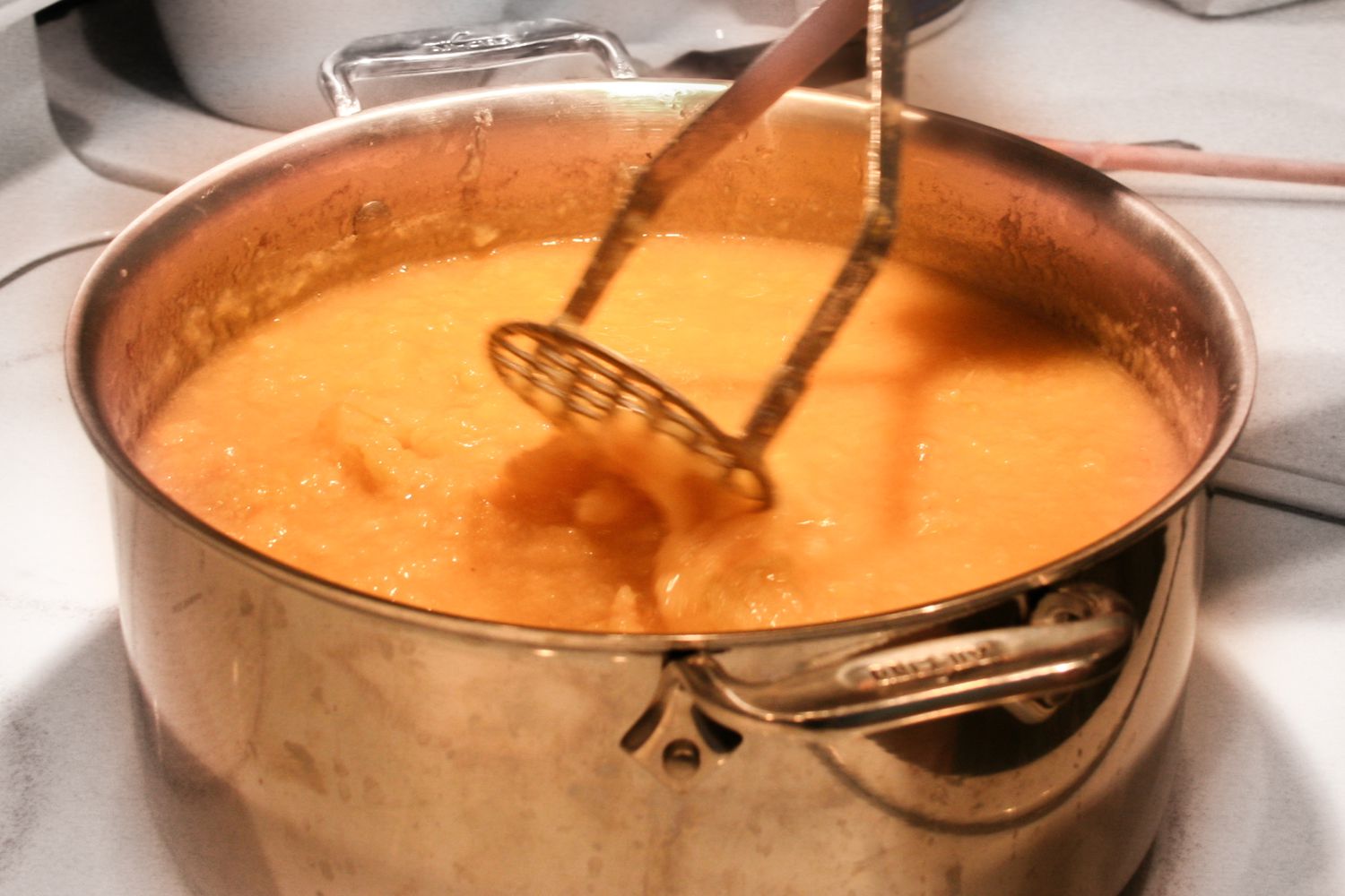 Mashing a pot of cooked quince 
