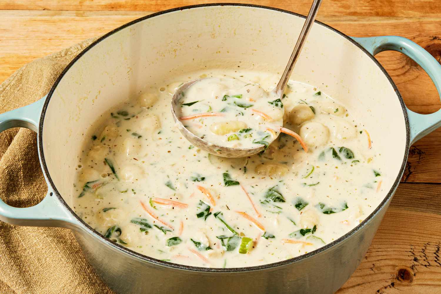 Copycat Olive Garden chicken and gnocchi soup in a Dutch oven with some lifted in a ladle 