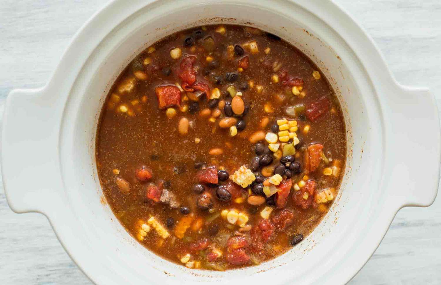 Stir together the ingredients for slow cooker taco soup in the crockpot insert