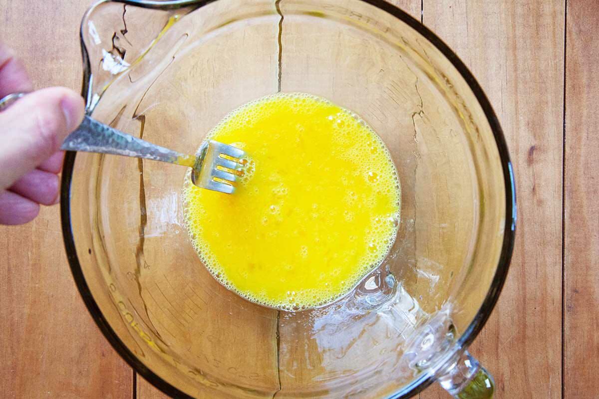 Egg mixed with a fork for the filling of the best chess pie.