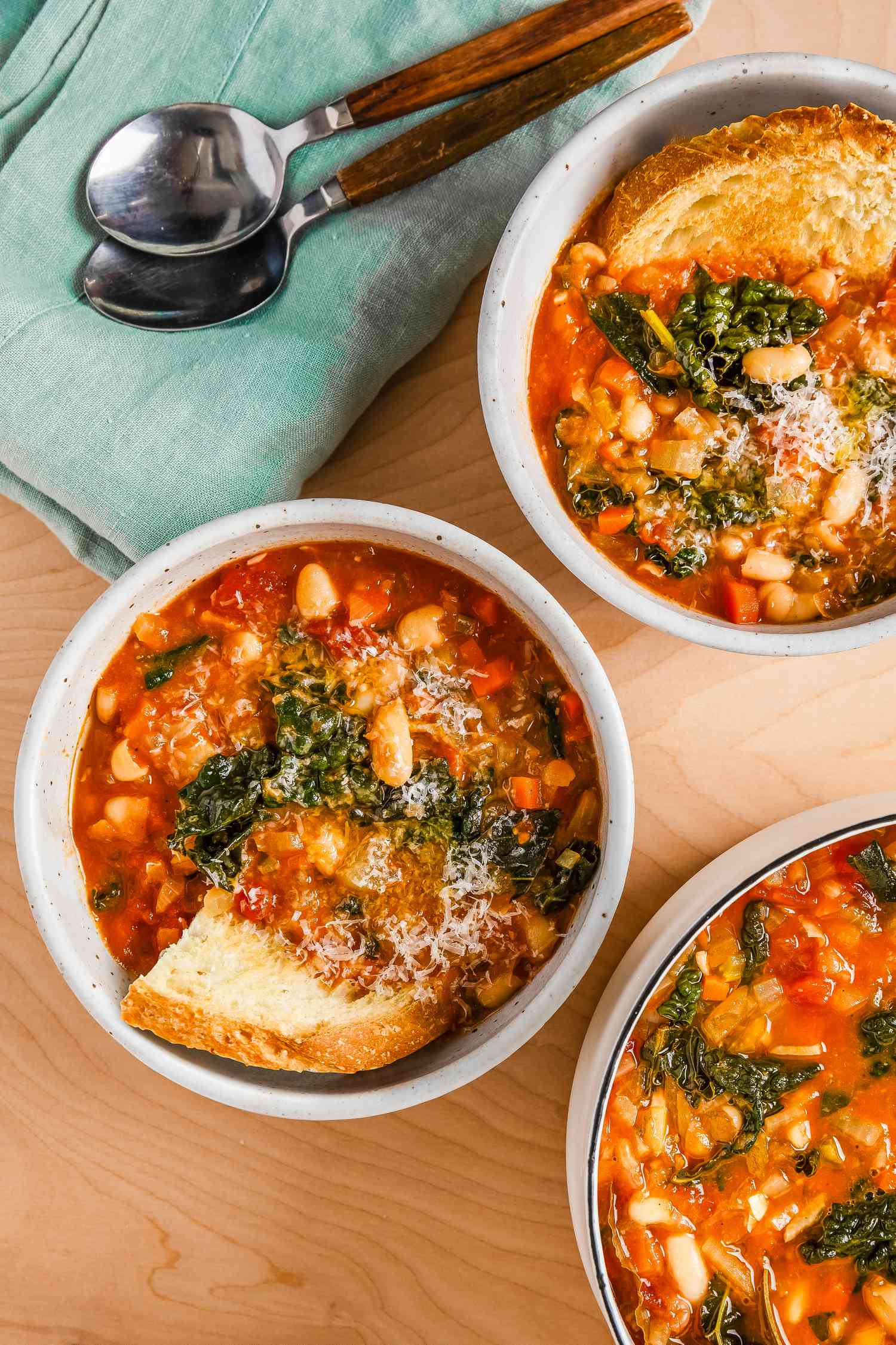 easy tuscan ribolitta soup at a table setting with another bowl, utensils on a table napkin, and a dutch oven