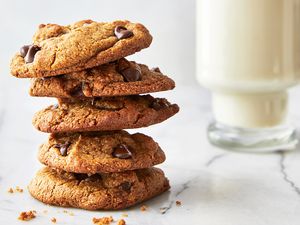 Stack of chocolate chip cookies on a marble surface glass of milk in the background