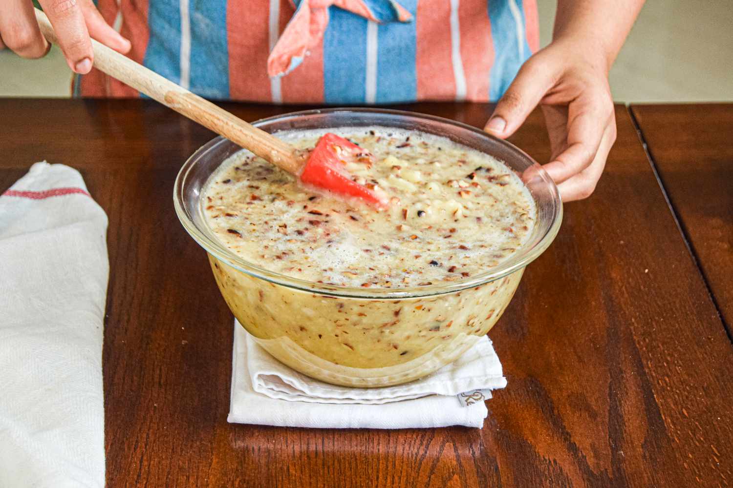 Mixing batter to make a hummingbird cake recipe in a glass bowl.