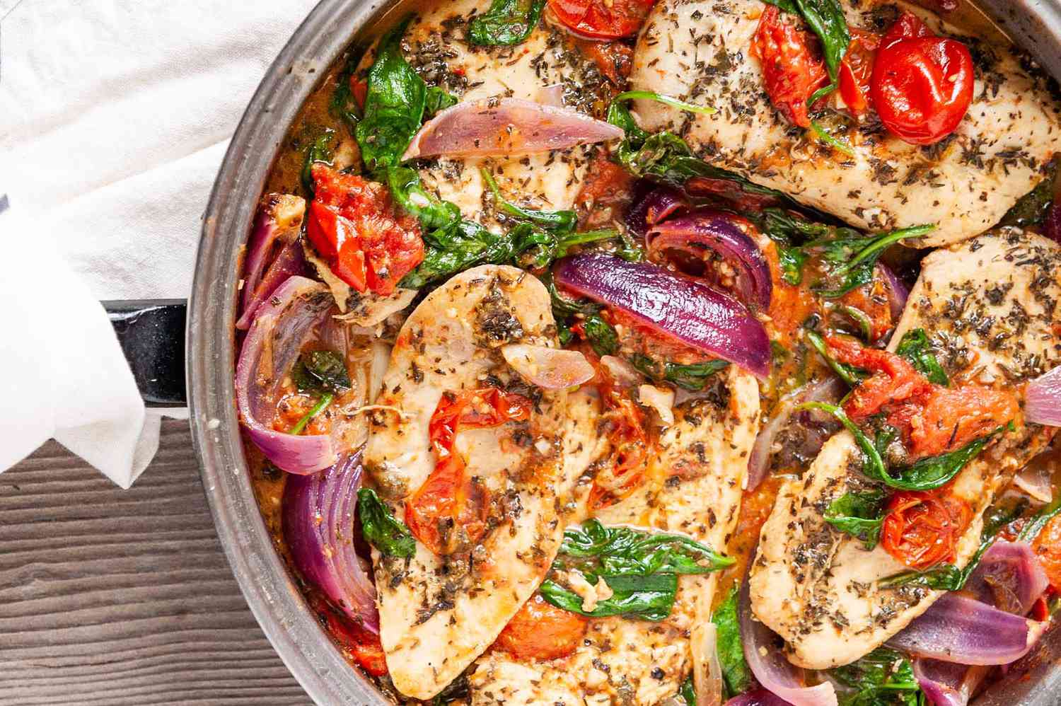 A skillet full of Italian Chicken with Spinach, Tomatoes, and Onions 