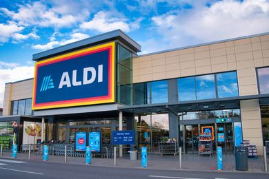 The exterior entrance of an Aldi grocery store under a blue sky
