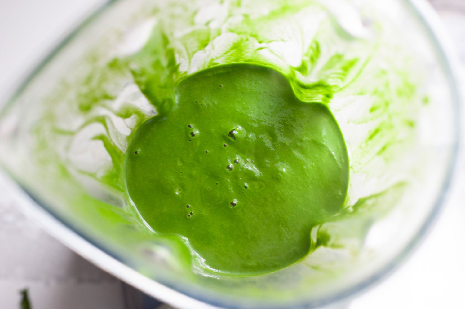 Bright green sauce in a blender to make a simple pasta with green sauce.