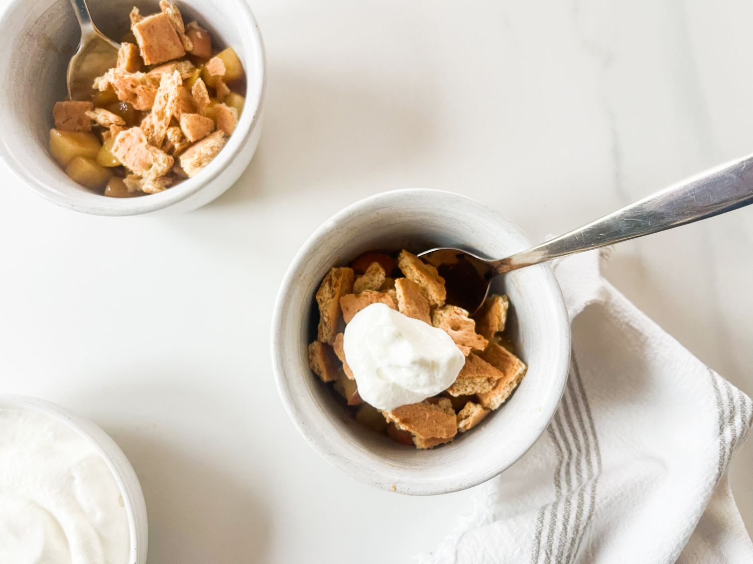 Prepared apple pie dessert served in bowls with whipped topping and utensils