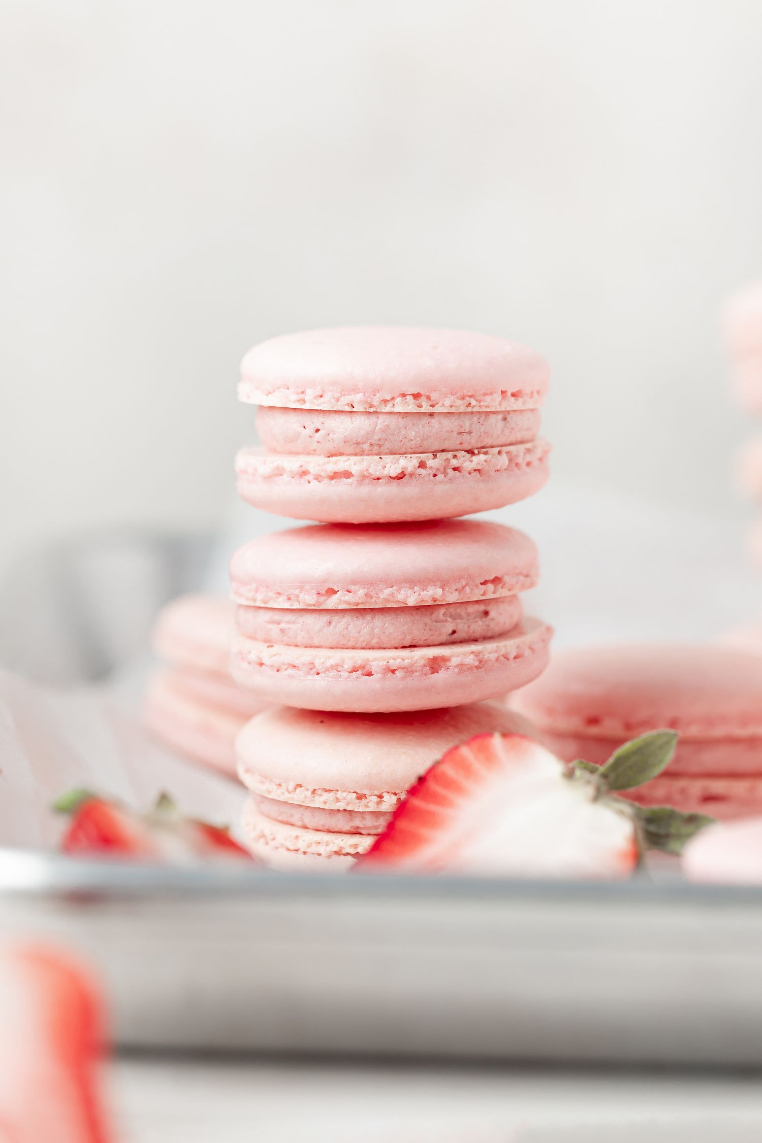 Close up side view of strawberry buttercream-filled macarons stacked on a plate