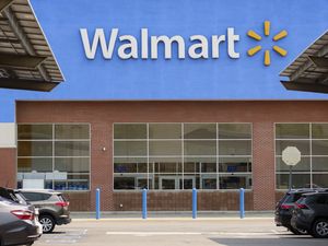 Exterior entrance to a Walmart store with parked cars in the foreground