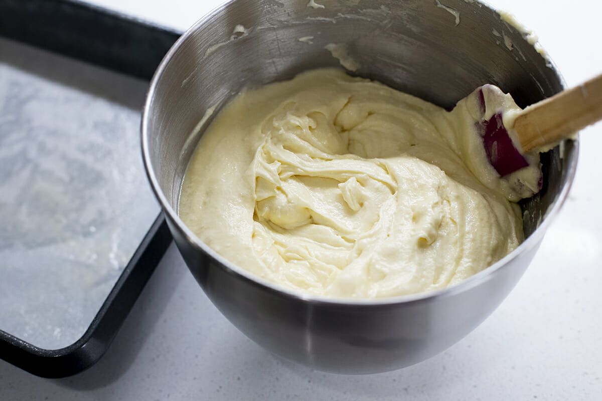 Cake batter in mixing bowl being stirred with a spatula 