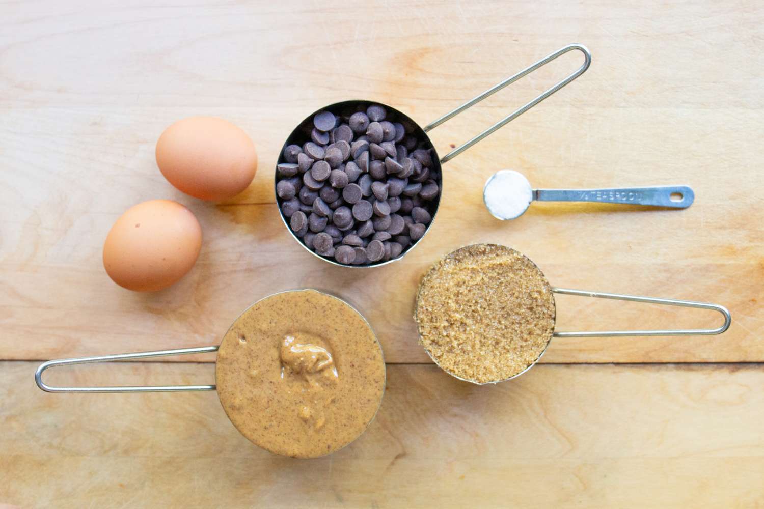 Ingredients arranged on a table including eggs chocolate chips and other baking items for making cookies