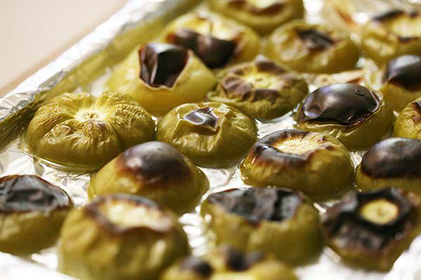 A foil-lined baking sheet with baked tomatillos on it