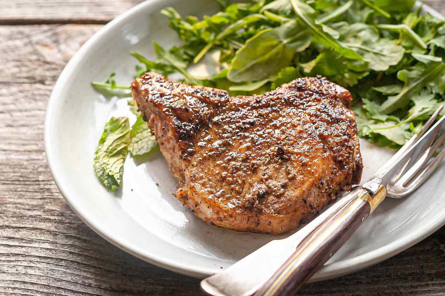 A plate with a pork chop and salad, ready to serve