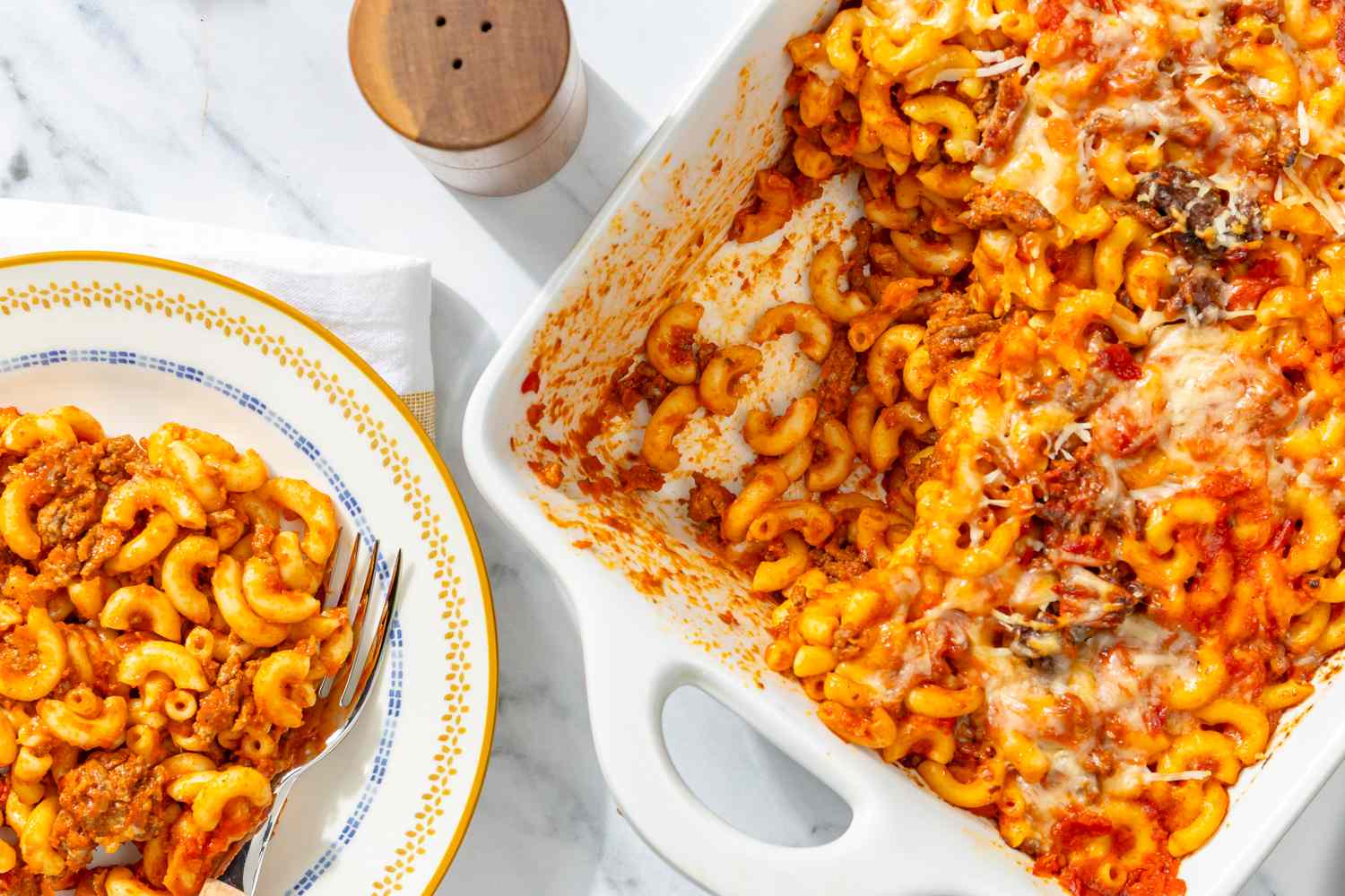 overhead view of a baking dish of Johnny Mac (4-Ingredient Casserole) and one serving scooped out onto a plate with a fork