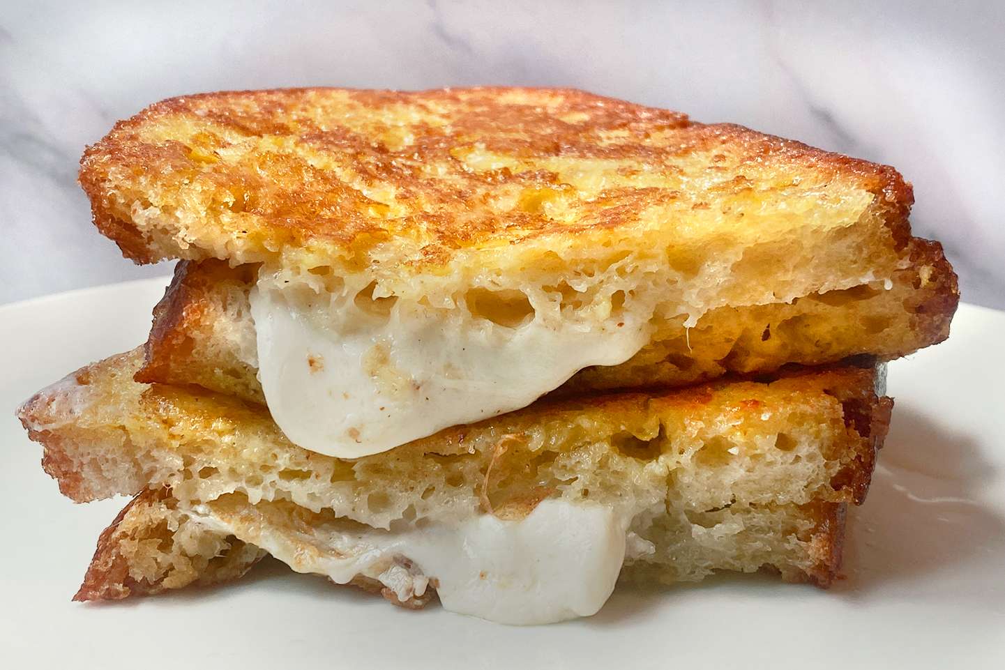 A stack of grilled cheese sandwich halves with melted cheese oozing out