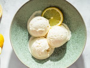 Bowl containing three scoops of lemon coconut sorbet garnished with a lemon slice
