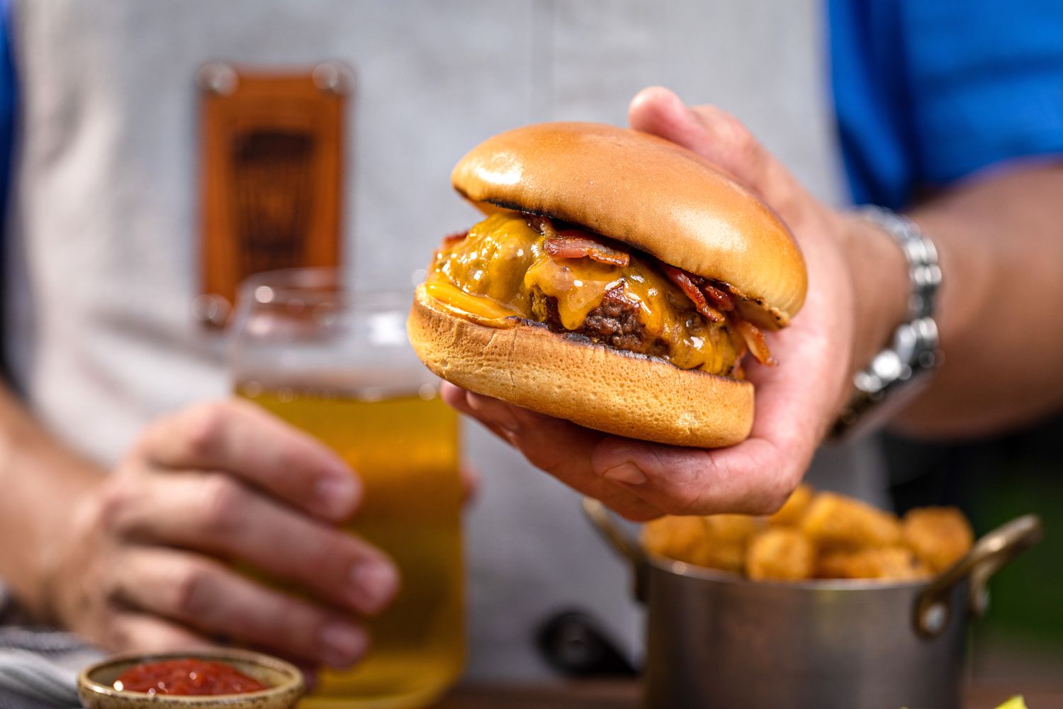 A person holding an ultimate bacon cheeseburger.