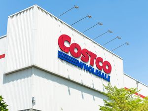 A Costco Wholesale sign on the exterior of a warehouse building viewed from a low angle