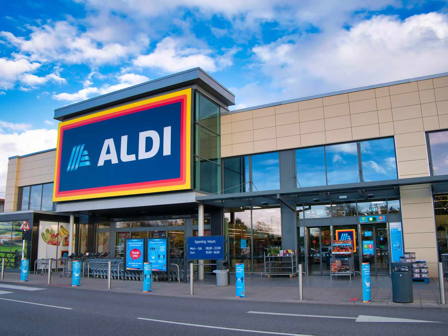 The exterior entrance of an Aldi grocery store under a blue sky