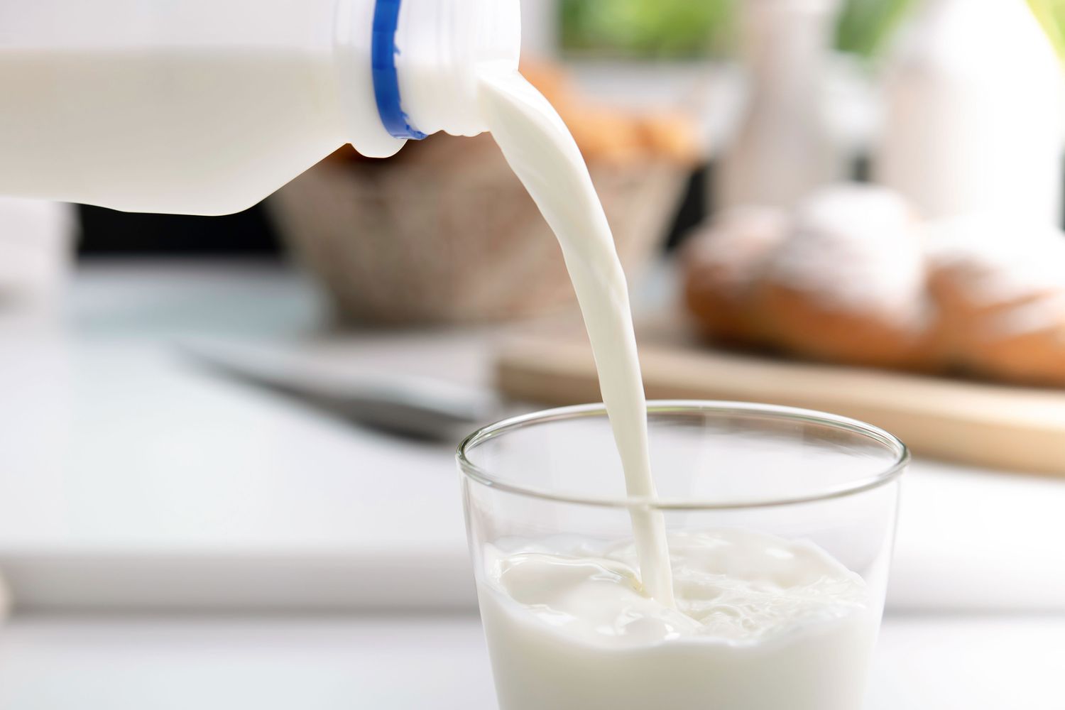 close up of milk jug with milk pouring into a glass