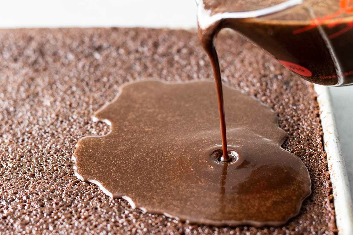 Easy Texas Sheet Cake pour on the frosting