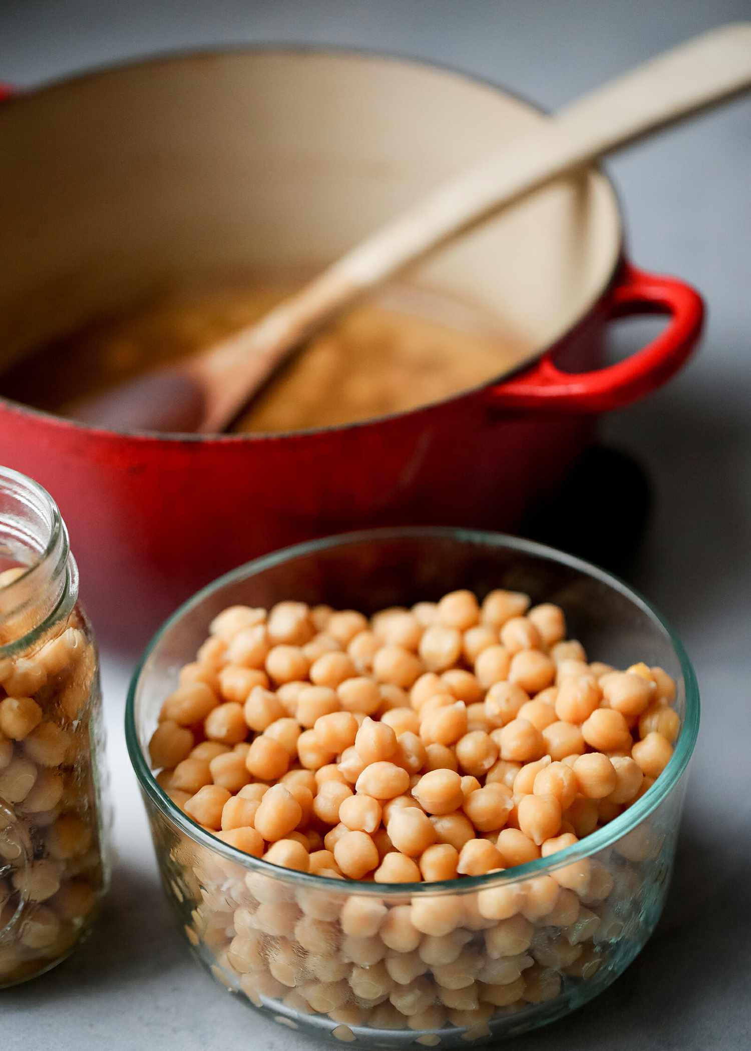 Cooked chickpeas in a glass container in front of a pot