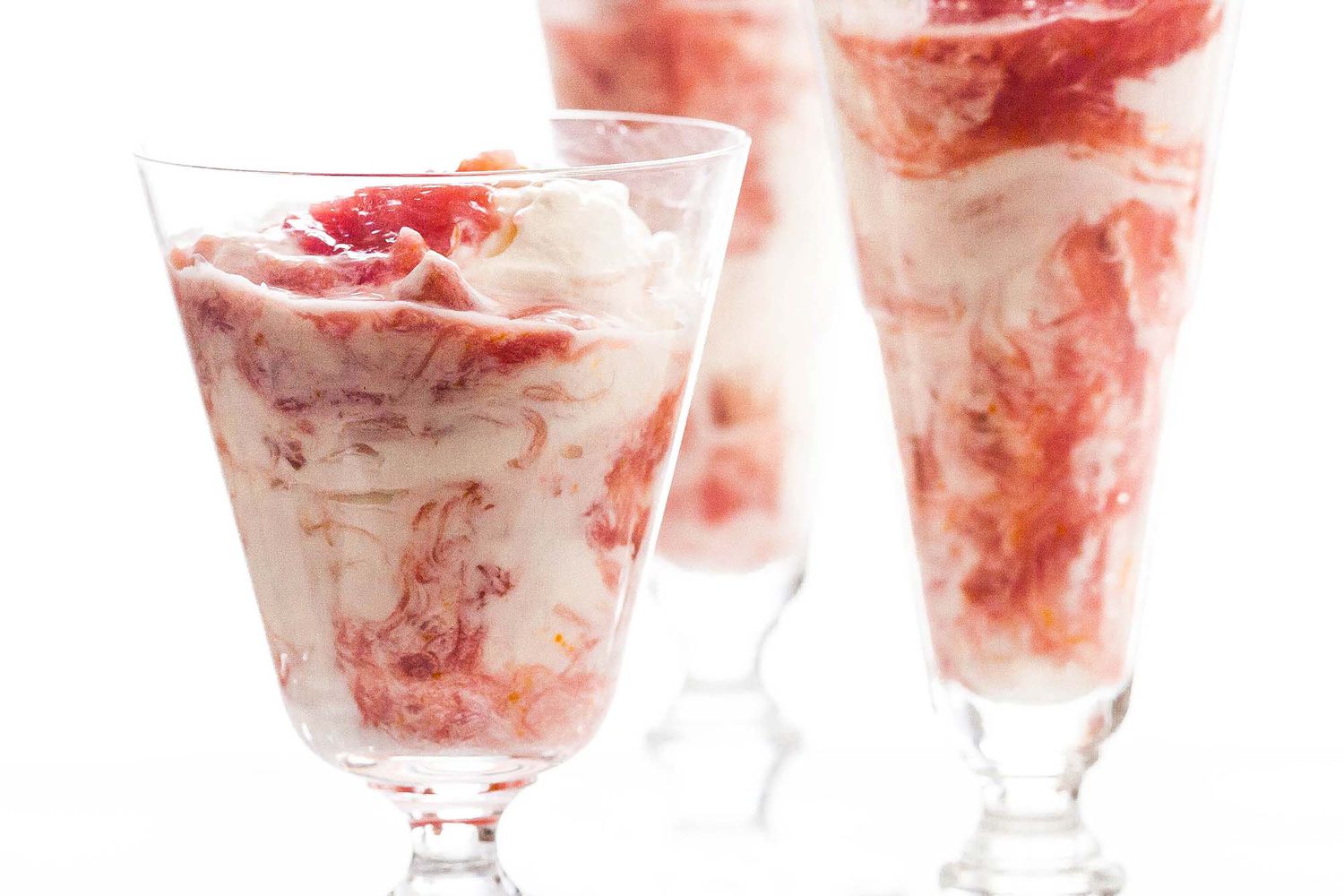 A side shot of a few tall clear glasses filled with rhubarb fool, ready to eat