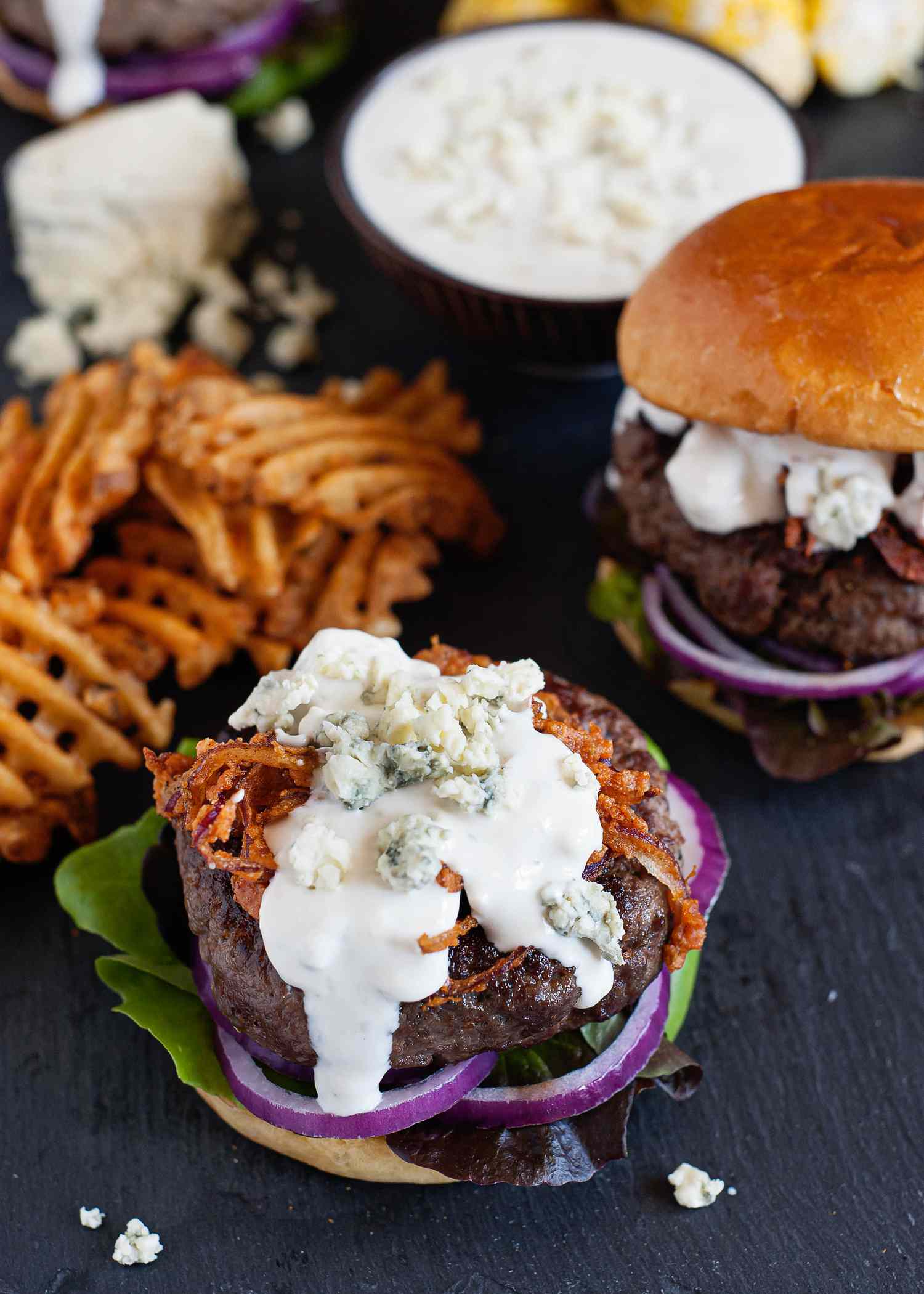 Homemade Blue Cheese Sauce - blue cheese sauce on a hamburger with fries in the background