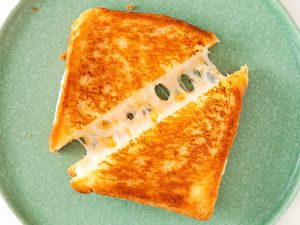 A grilled cheese sandwich cut in half placed on a plate