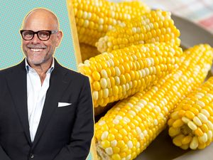 Alton Brown alongside a plate of corn on the cob