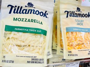 Packages of Tillamook shredded mozzarella and Colby Jack cheese on a store shelf