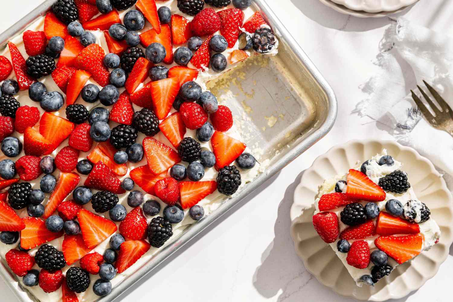 Easy Berry Chantilly Cake in a tin, one slice removed and set on a dessert plate with a fork