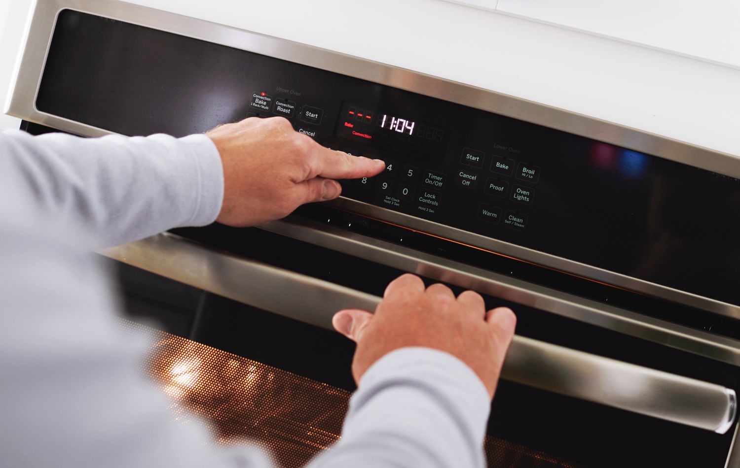 Hands adjusting the controls on an oven to preheat