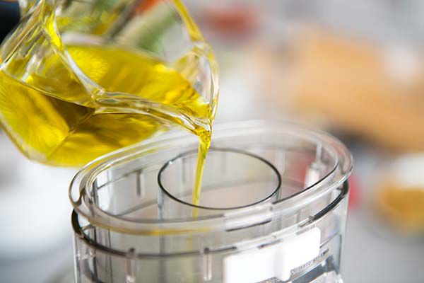 Olive oil being poured into a food processor 