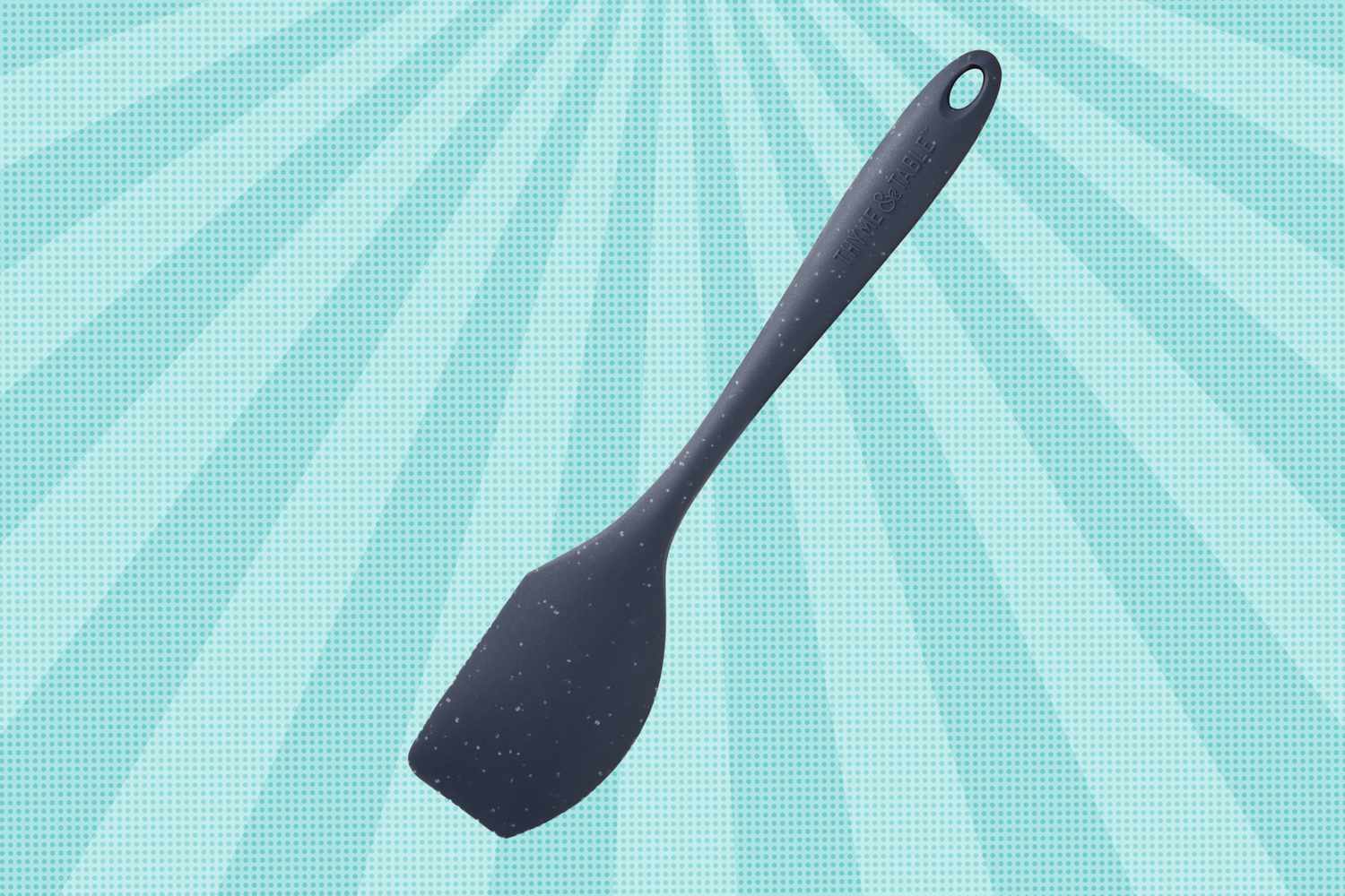 A kitchen spatula with a textured handle and a hole at the end displayed against a patterned background