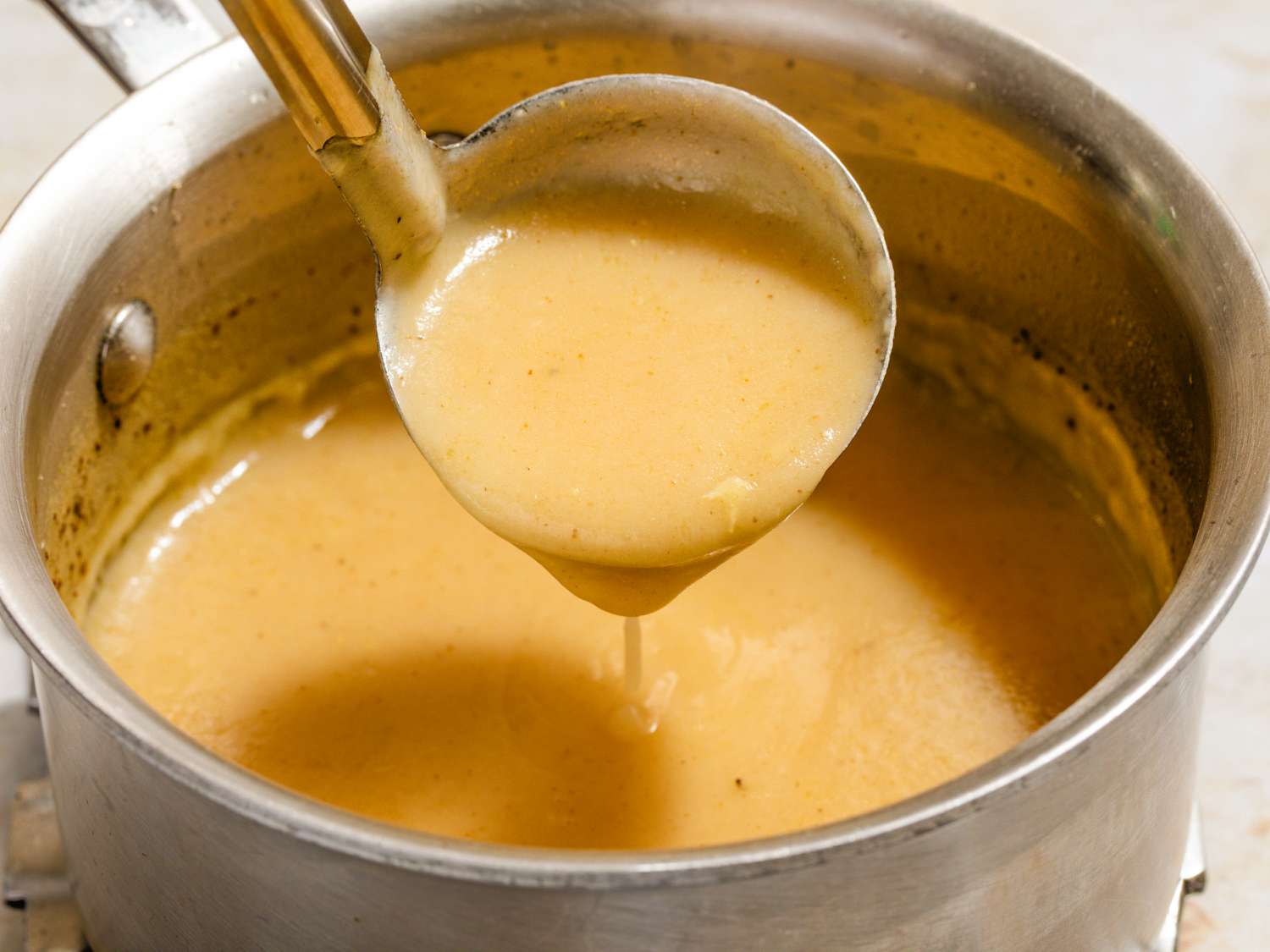 Angled view of a pot of 3-ingredient gravy with a ladle removing a serving