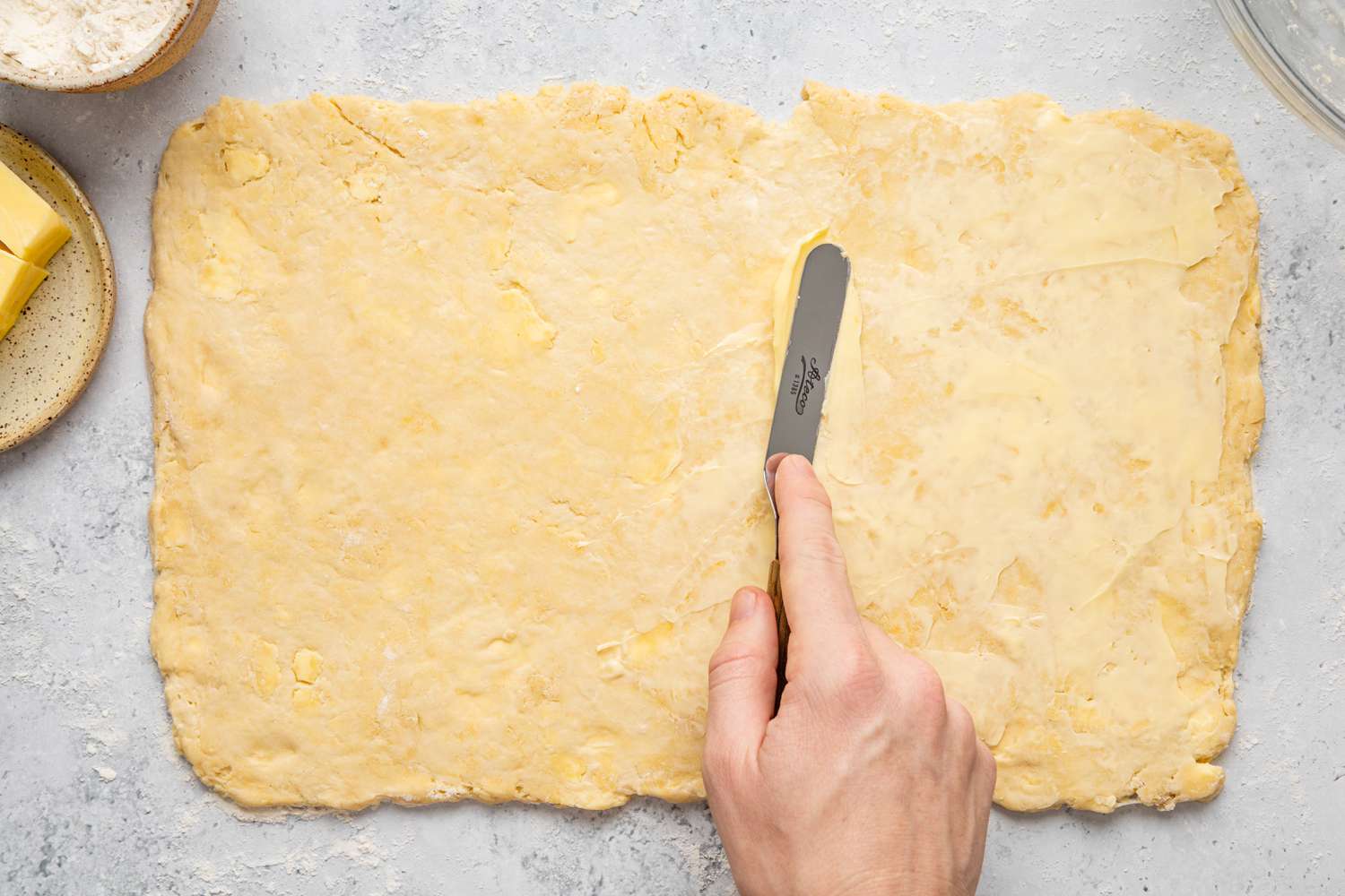 Homemade Crescent Roll Dough Rolled onto a Surface and Covered in Butter for Lamination Steps