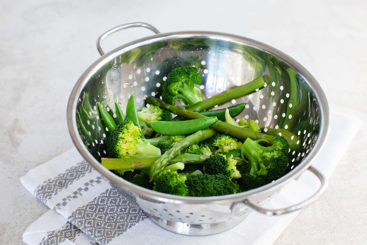 Blanched broccoli in a strainer for a pasta primavera recipe.