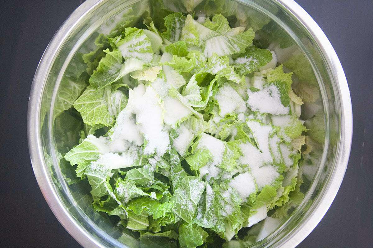 Napa cabbage in a mixing bowl and topped with salt for a Korean kimchi recipe.