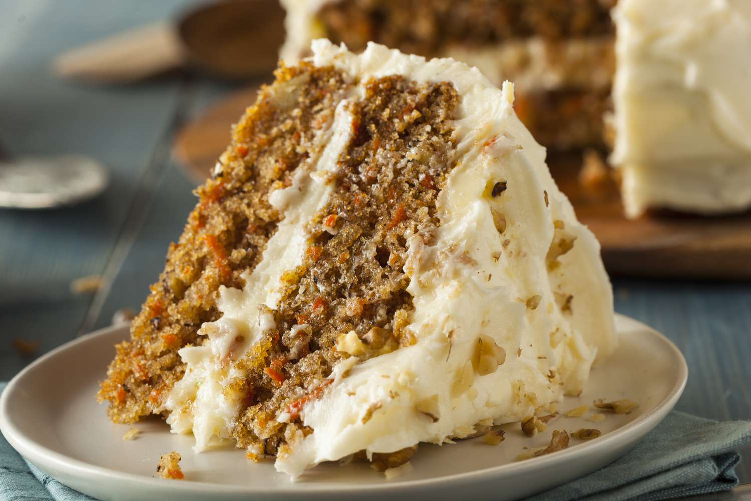 Sideview of a big slice of a two layer carrot cake on a plate