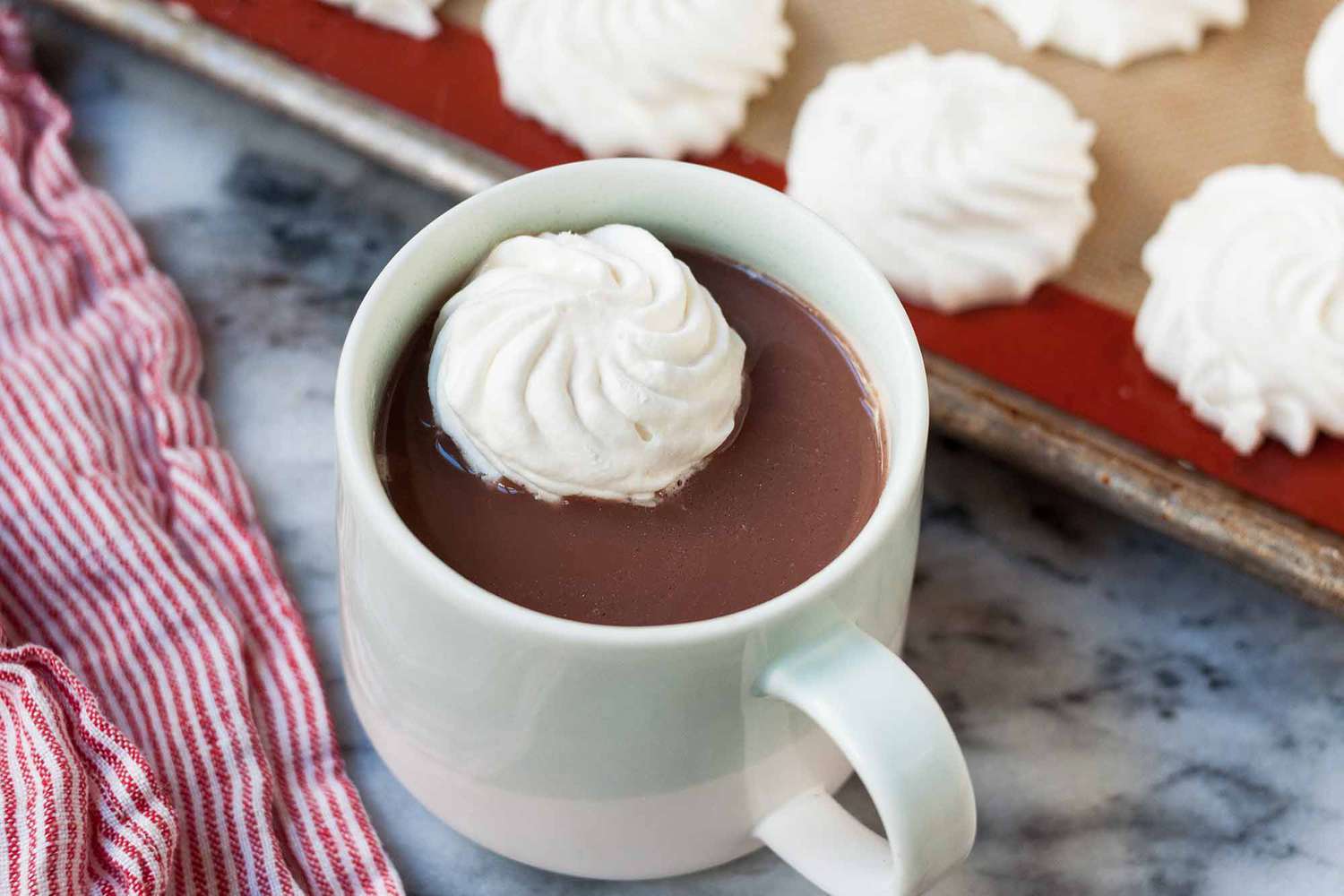 frozen dollop of whipped cream in a cup of hot cocoa