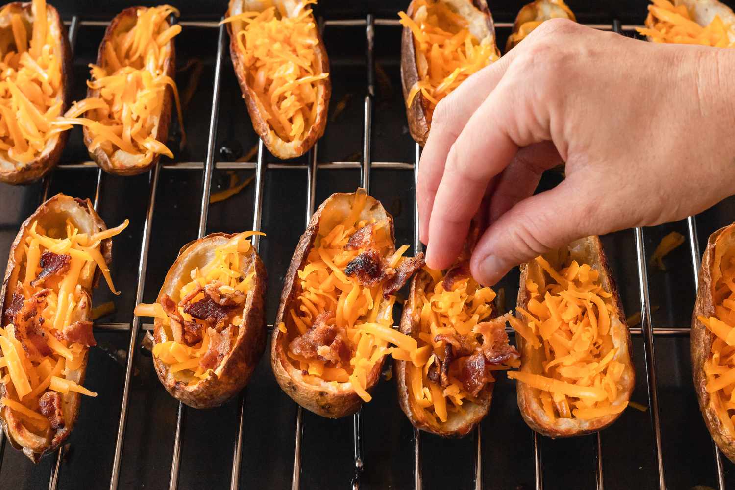 Topping potato skins with cheese and bacon.