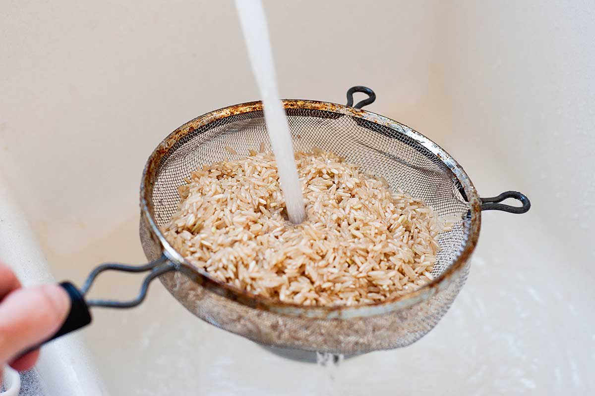 Rinsing brown rice in a fine mesh sieve