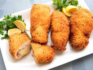 Homemade Chicken Cordon Bleu on a white platter with lemon wedges.