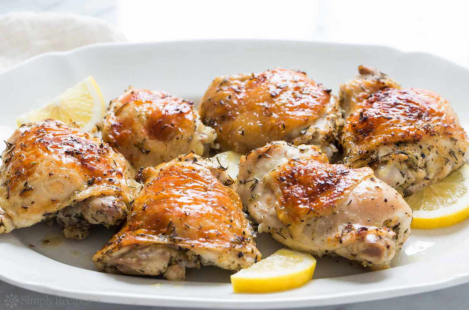 A side view of lemon chicken on a platter with lemon slices