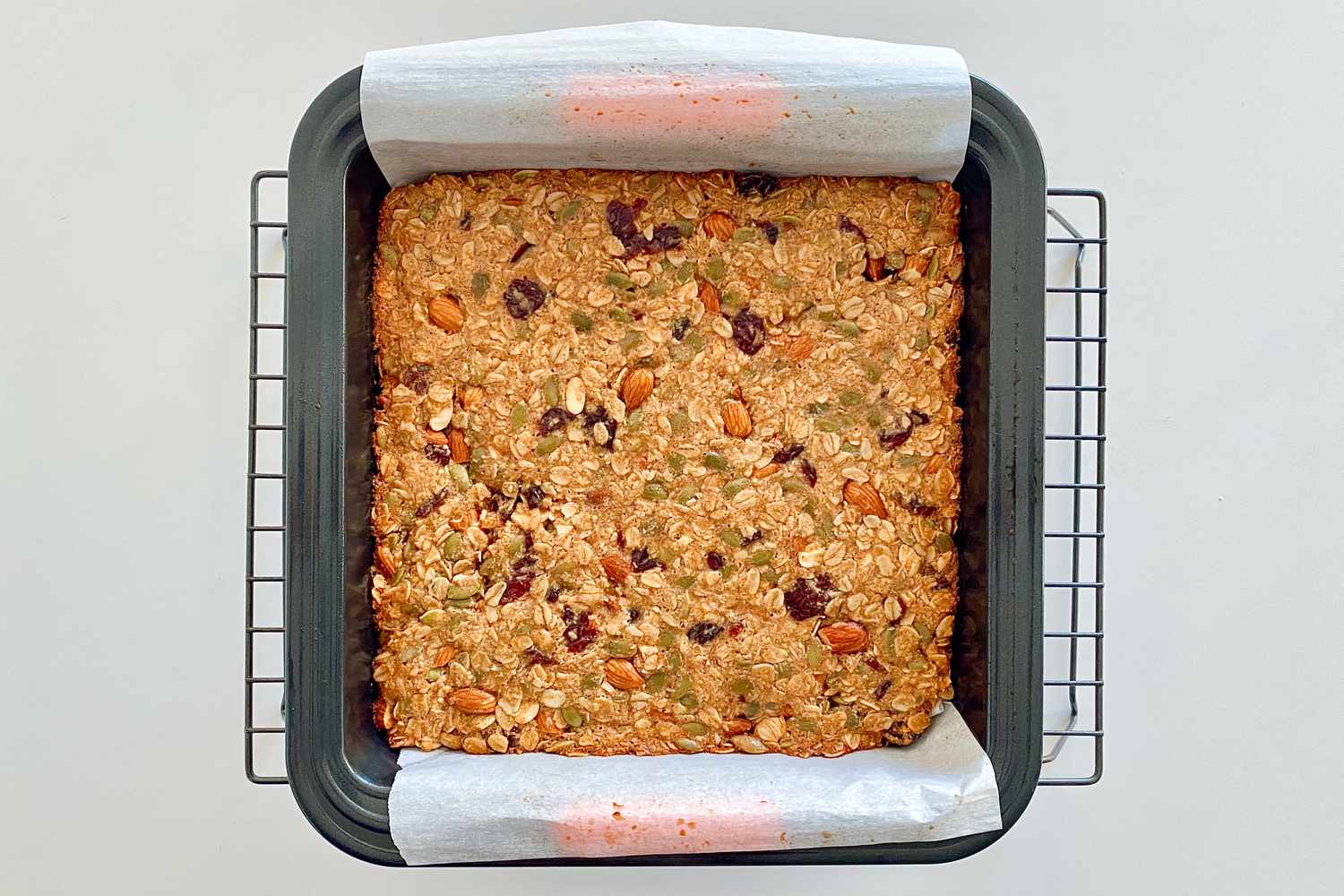 Homemade Chewy Granola Bars baked in a pan and set on a cooling rack.