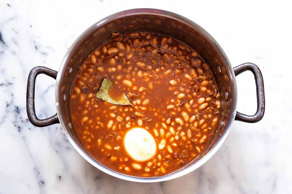 Baked Beans on the Stovetop - baked beans in a pot with onion and bay leaf